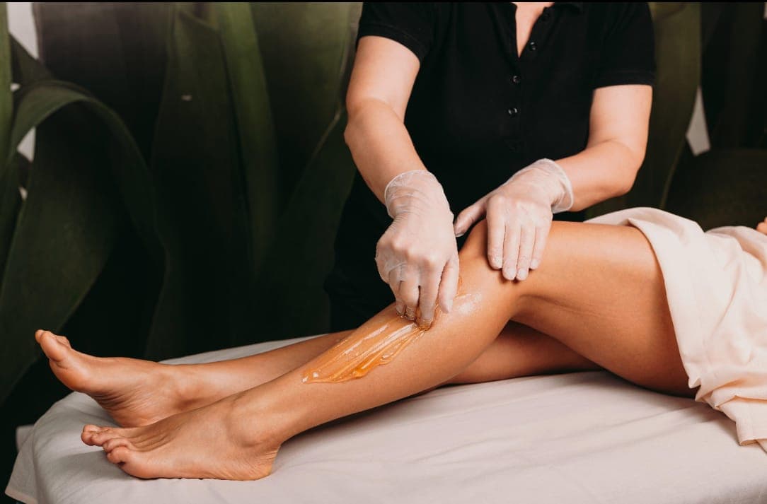 Close up of a leg waxing treatment with warm wax being applied in a styled studio setting