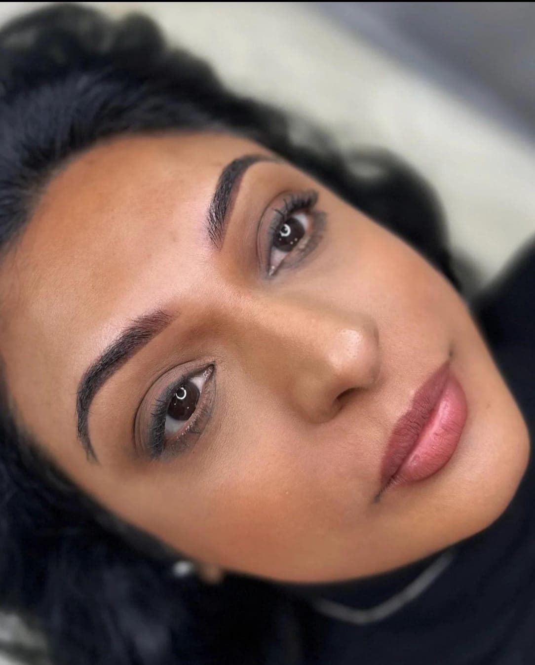 Close up of a client's face with well groomed, defined brows and soft glam makeup